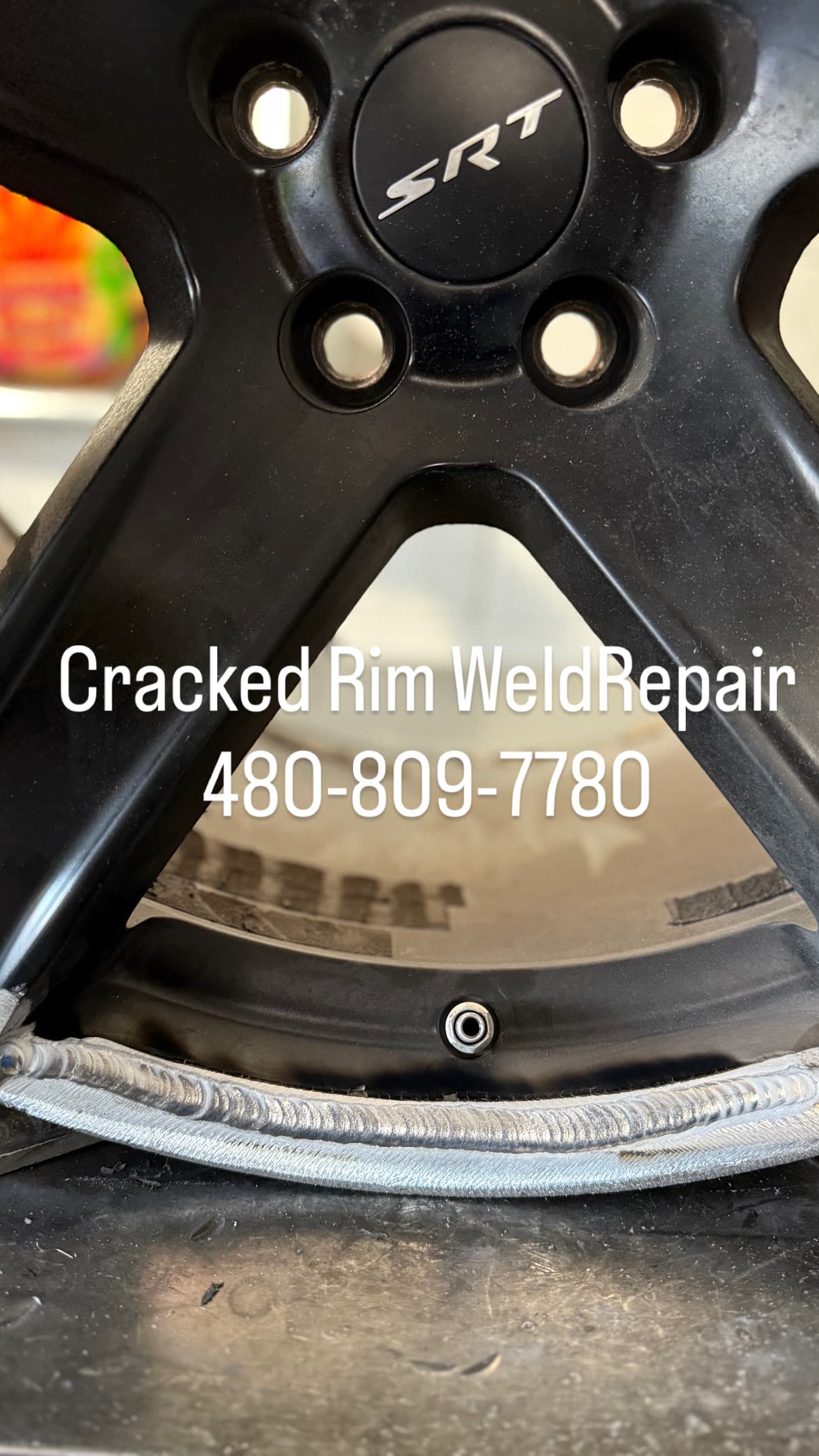 Black SRT rim with a silver weld repair on the inner edge and service number.